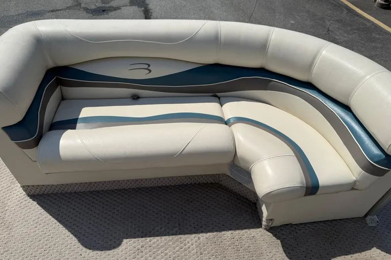 Slide: The Image of 2005 Bennington 2075RL boat seating with white and blue upholstery on a textured deck. - 8
