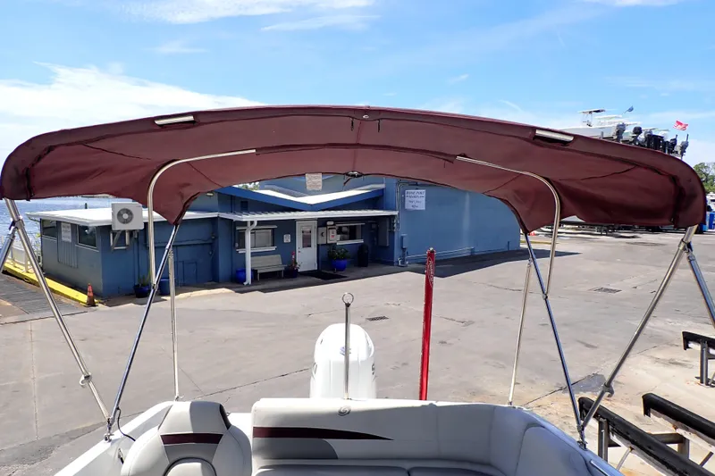 Slide: The Image of 2021 Hurricane SunDeck Sport 185 OB boat with maroon canopy at dockside. - 21