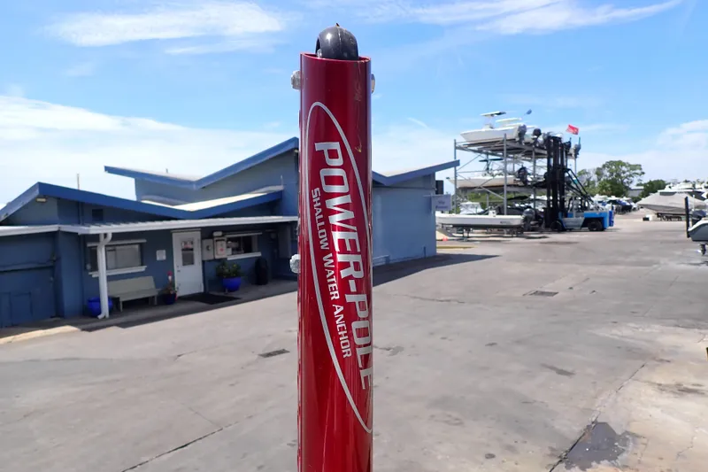 Slide: The Image of Red Power-Pole shallow water anchor at a marina, with boats and buildings in the background. - 28