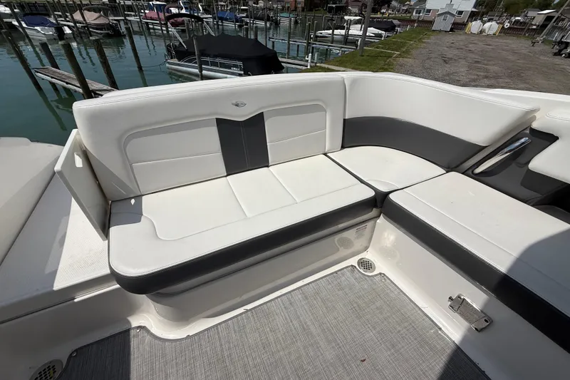 Slide: The Image of 2016 Chaparral 307 SSX boat interior with white and gray seating at a marina. - 10