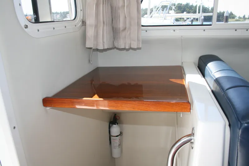 Slide: The Image of Interior of 2014 Ocean Sport 27' Legacy boat with wooden table and blue seating. - 15