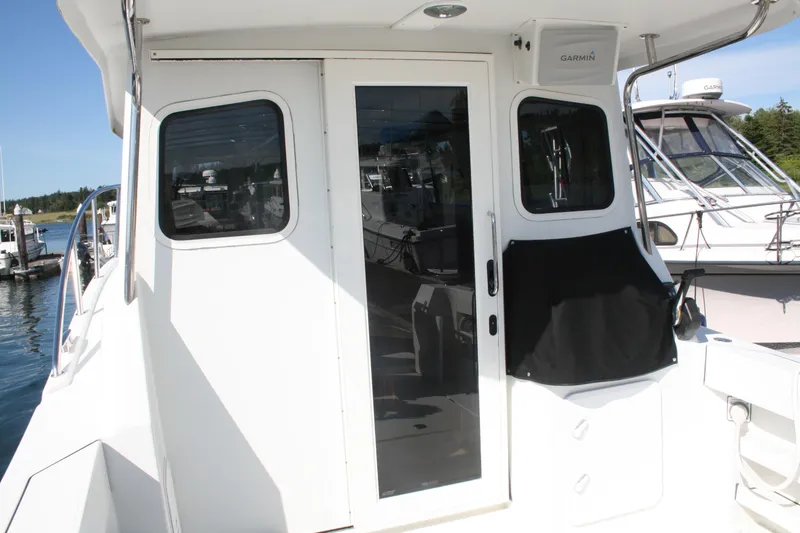 Slide: The Image of Ocean Sport 27' Legacy 2014 boat with white exterior, docked at a marina. - 2
