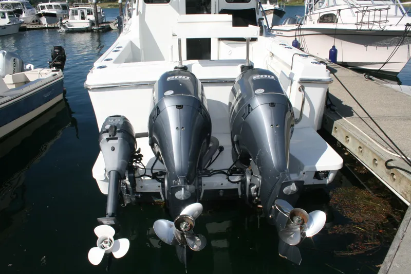 Slide: The Image of 2014 Ocean Sport 27' Legacy boat with triple outboard motors docked at marina. - 20