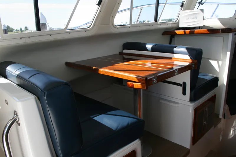 Slide: The Image of Interior of 2014 Ocean Sport 27' Legacy boat with wooden table and blue seating. - 9