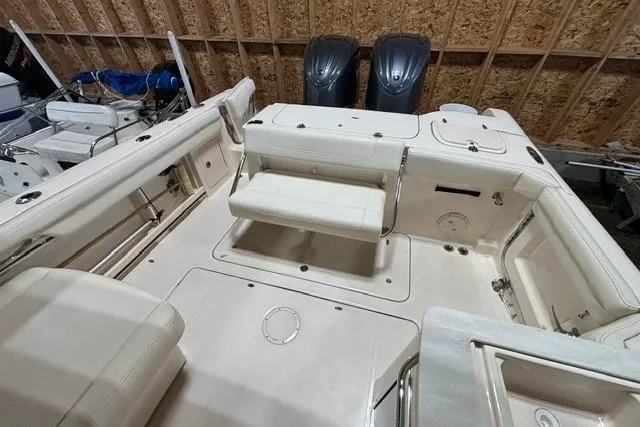 Slide: The Image of 2022 Grady-White Freedom 285 boat interior with seating and dual engines in a wooden garage. - 19