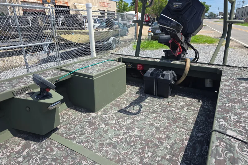 Slide: The Image of 2015 Gator Tail 1854 boat interior with camouflage pattern and motor, parked near a fence. - 4