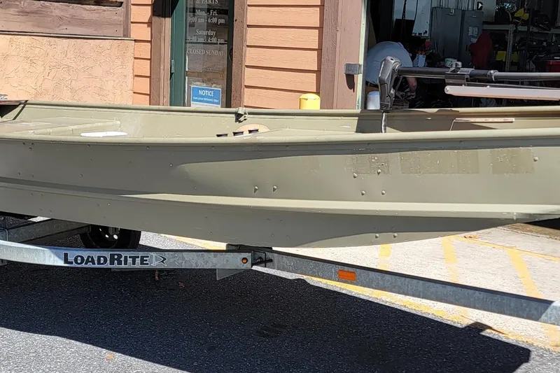 The Image of 2015 Tracker Topper 1542 LW Riveted Jon boat on LoadRite trailer outside a building. - 1