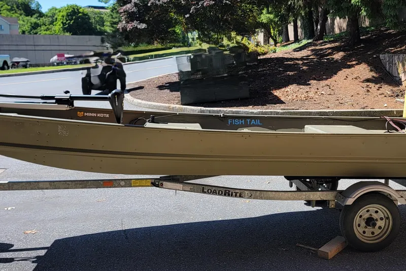 Slide: The Image of 2015 Tracker Topper 1542 LW Riveted Jon boat on trailer, parked outdoors. - 11