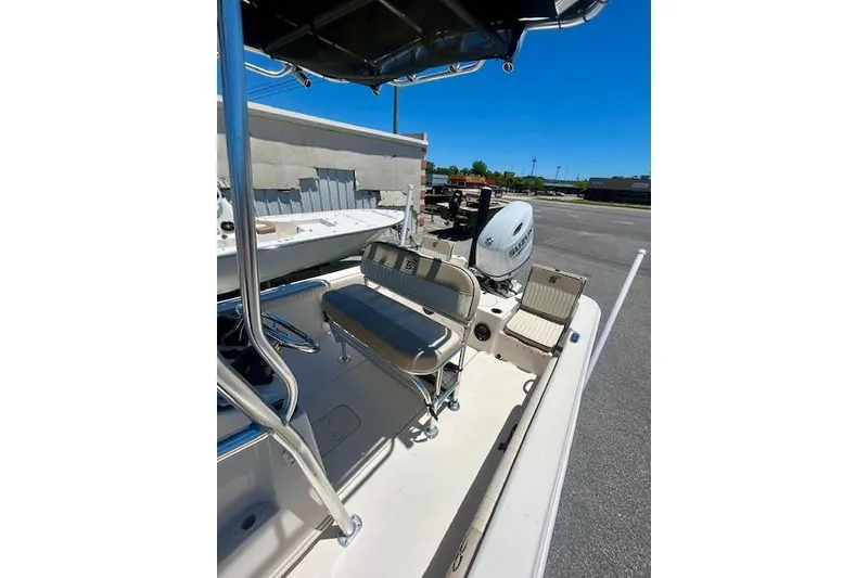 Slide: The Image of 2022 Carolina Skiff 21 LS boat interior with seating and motor, parked outdoors. - 15