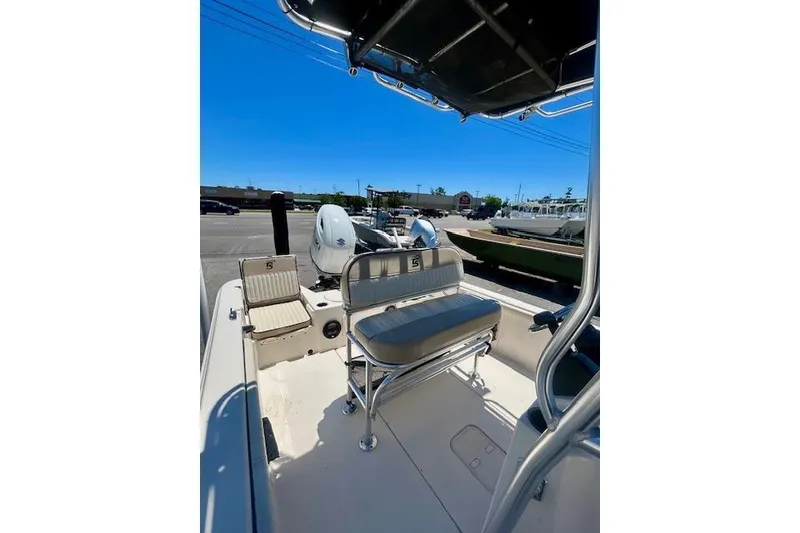 Slide: The Image of 2022 Carolina Skiff 21 LS boat interior with seating and console, parked outdoors. - 17