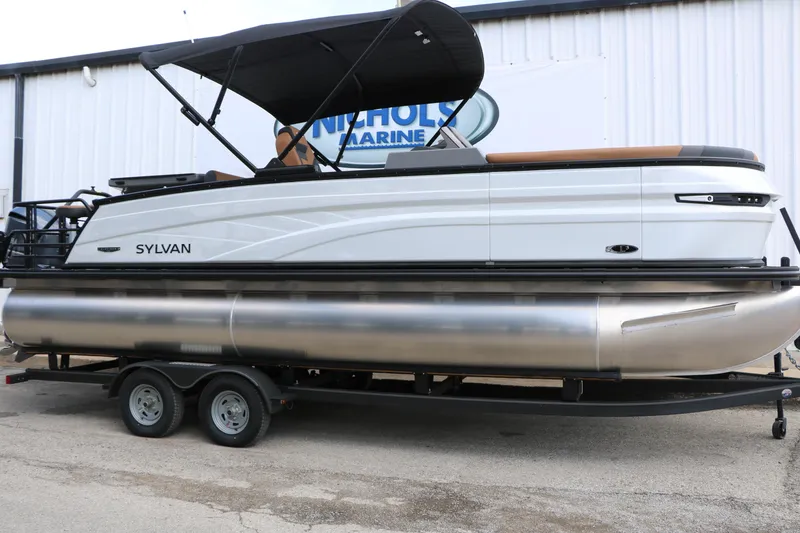 Slide: The Image of 2026 Sylvan L3 DLZ Bar Platinum Edition Tri-Toon boat on trailer, side view. - 2