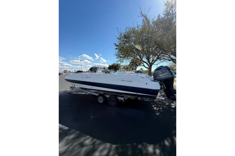 The Image of 2015 Hurricane SunDeck Sport CC 231 OB boat on trailer under clear blue sky. - 1