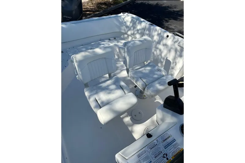 Slide: The Image of 2015 Hurricane SunDeck Sport CC 231 OB boat interior with white seating and controls. - 11