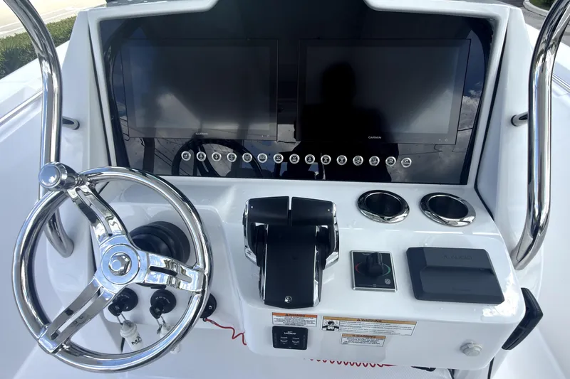 Slide: The Image of 2023 Bertram 28 CC boat dashboard with dual screens and steering wheel. - 18