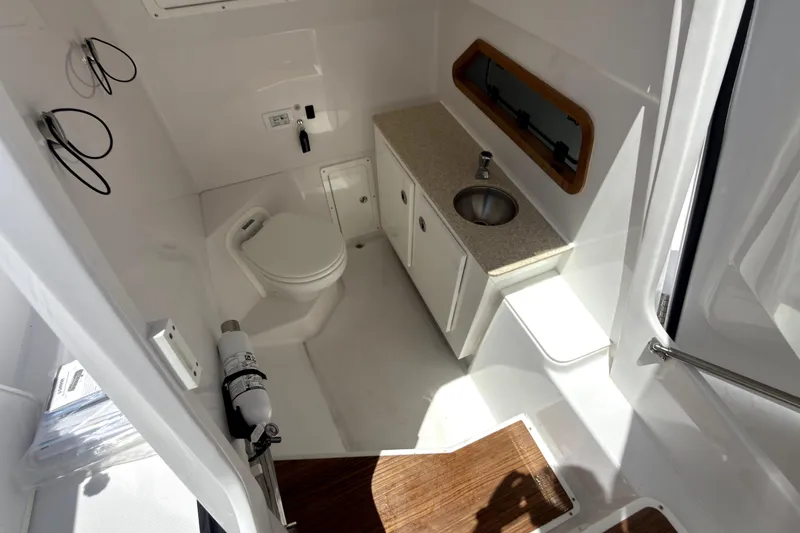 Slide: The Image of 2023 Bertram 28 CC boat interior with toilet, sink, and storage cabinets. - 28