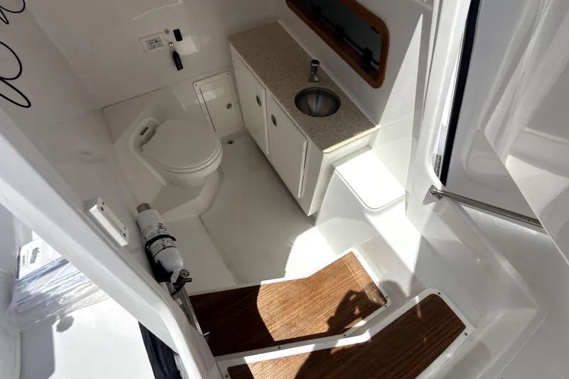 Slide: The Image of 2023 Bertram 28 CC boat interior with toilet, sink, and wooden steps. - 29