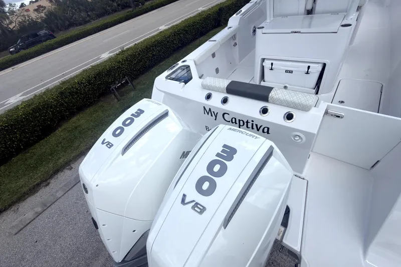 Slide: The Image of 2023 Bertram 28 CC boat with twin Mercury 300 V8 engines, docked near a road. - 4