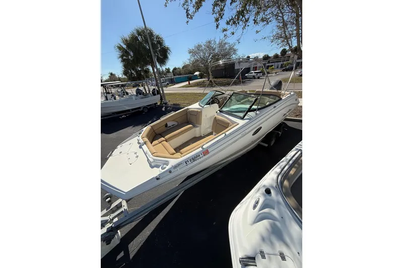 Slide: The Image of 2020 NauticStar 243 DC boat with tan seating on a trailer, parked outdoors. - 4