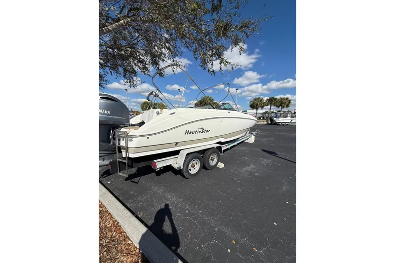 Slide: The Image of 2020 NauticStar 243 DC boat on trailer under clear blue sky. - 7