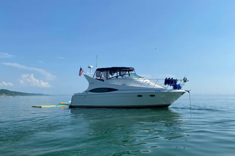 The Image of 1998 Carver 350 Mariner yacht anchored on calm water under clear blue sky. - 0