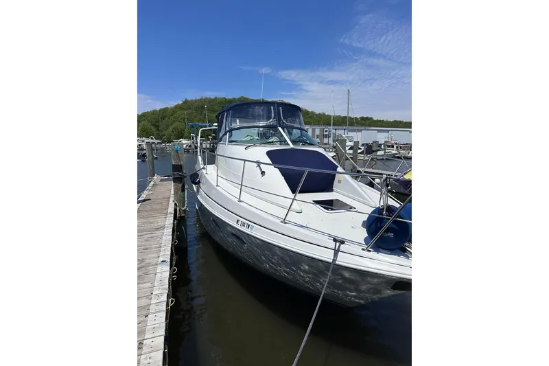 Slide: The Image of 1998 Carver 350 Mariner docked at a marina, featuring sleek white design and blue canopy. - 4