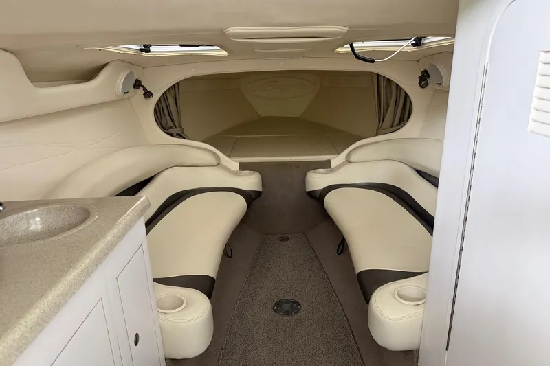 Slide: The Image of Interior of a 2001 Baja 33 Outlaw boat, featuring beige seating and compact cabin amenities. - 14