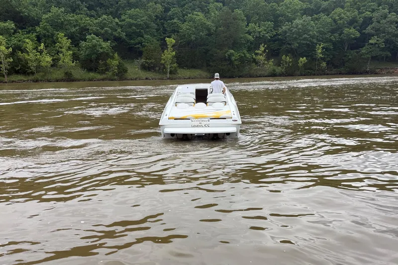 Slide: The Image of 2001 Baja 33 Outlaw boat cruising on a river with lush green forest backdrop. - 2