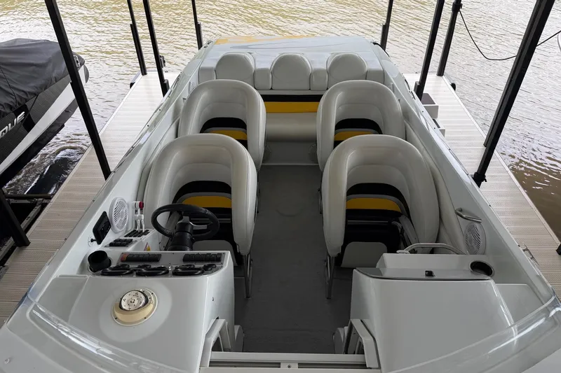 Slide: The Image of 2001 Baja 33 Outlaw boat interior with seating and steering wheel, docked by the water. - 5