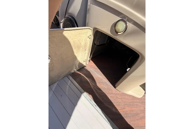 Slide: The Image of Open storage compartment on 2017 South Bay 523RS boat, featuring wood flooring and beige interior. - 5