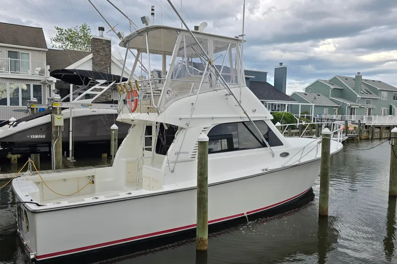 The Image of 2003 Henriques 35 Sportfisherman docked in a marina, surrounded by waterfront homes. - 0