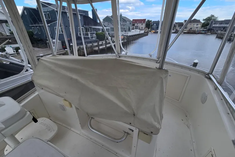 Slide: The Image of 2003 Henriques 35 Sportfisherman boat interior with covered helm, docked near waterfront homes. - 14