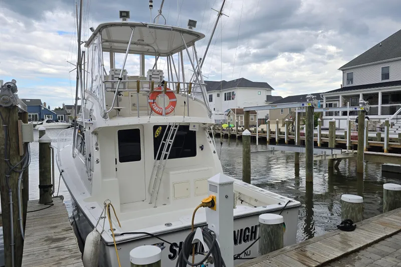 Slide: The Image of 2003 Henriques 35 Sportfisherman docked at a marina, surrounded by waterfront homes. - 4