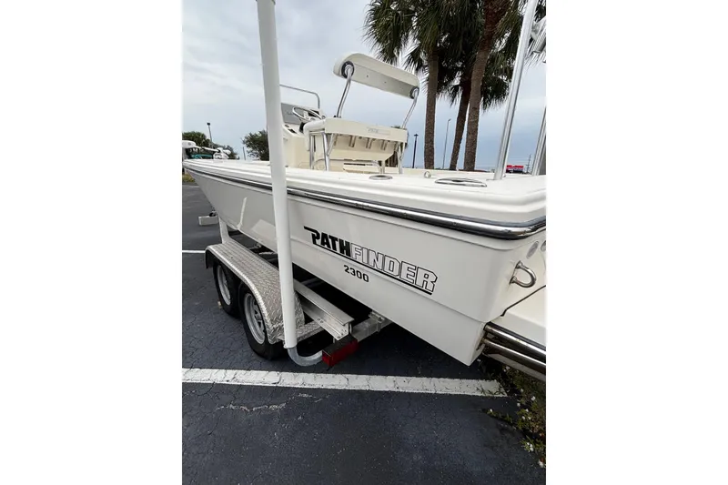 Slide: The Image of 2021 Pathfinder 2300 HPS boat on trailer, parked near palm trees. - 3
