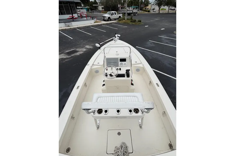 Slide: The Image of 2021 Pathfinder 2300 HPS boat interior with steering console and seating in a parking lot. - 7