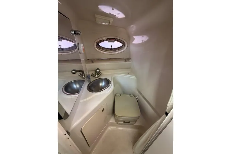 Slide: The Image of 2007 Sea Ray 240 Sundancer bathroom with sink, toilet, and porthole windows. - 13