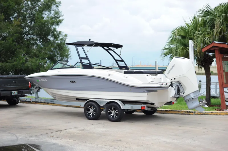 Slide: The Image of 2023 Sea Ray SPX 210 Outboard boat on trailer near waterfront. - 2