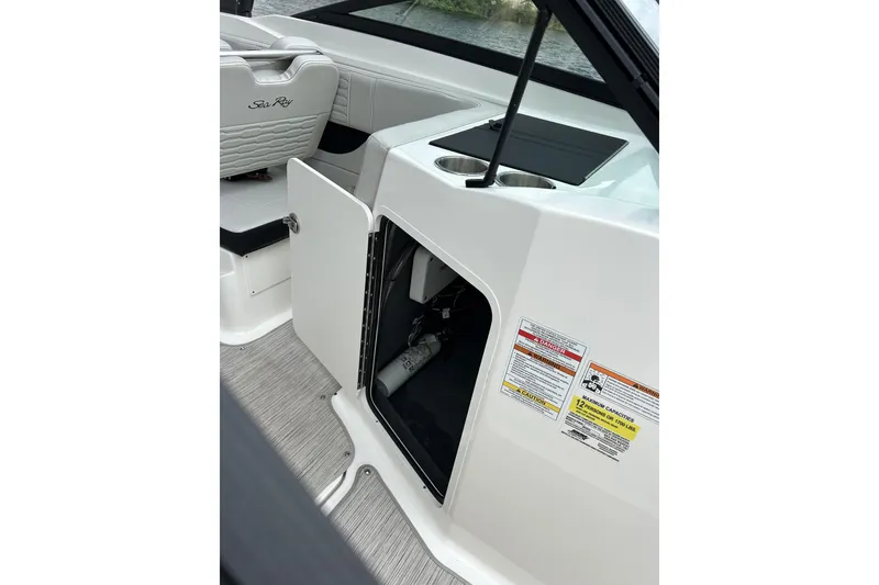 Slide: The Image of 2023 Sea Ray SPX 210 Outboard interior storage compartment with safety labels. - 7