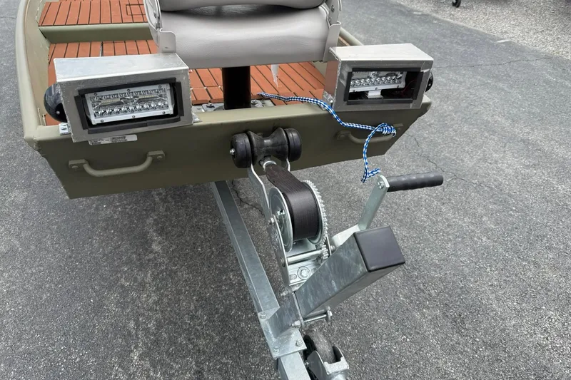 Slide: The Image of 2025 Tracker Grizzly 1542 boat trailer with winch and LED lights on asphalt. - 6