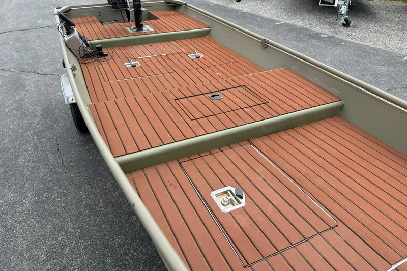 Slide: The Image of 2025 Tracker Grizzly 1542 boat with wooden deck, parked on pavement. - 8
