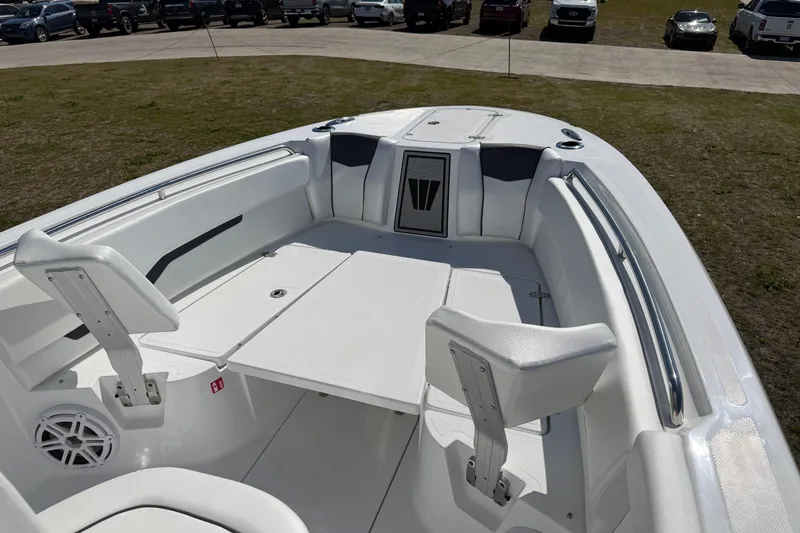 Slide: The Image of 2026 Wellcraft 243 Fisherman boat interior with seating and storage, parked on grass. - 4