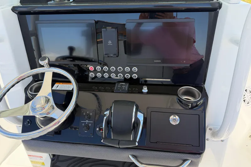 Slide: The Image of 2026 Wellcraft 243 Fisherman dashboard with dual Garmin displays and steering wheel. - 8
