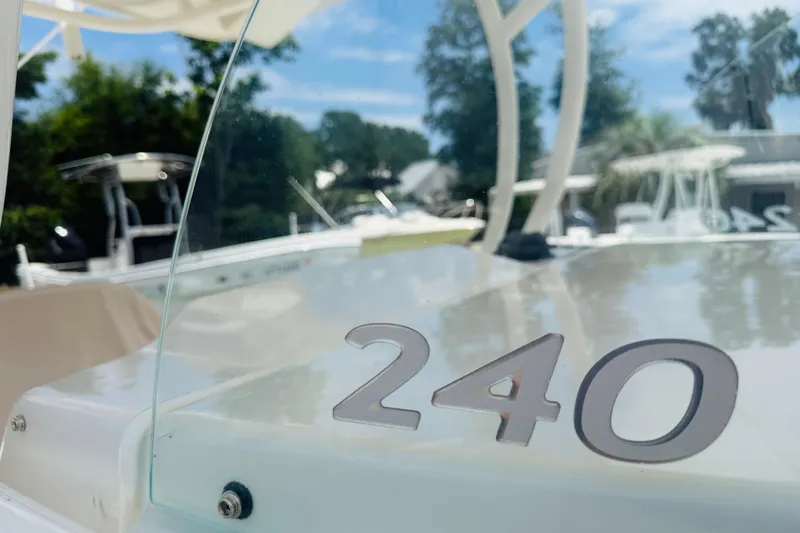 Slide: The Image of 2015 Sailfish 240 CC boat with clear windshield, outdoors in a marina setting. - 15