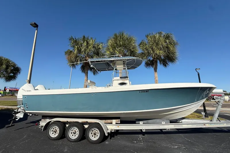 The Image of 2005 Bluewater 2850 CC boat on trailer, parked near palm trees under clear blue sky. - 1