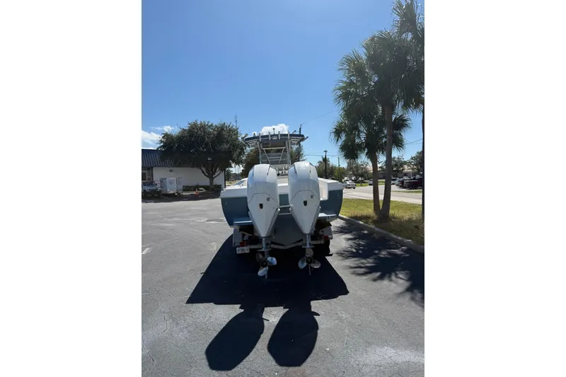 Slide: The Image of 2005 Bluewater 2850 CC boat with dual outboard motors parked under clear sky. - 3