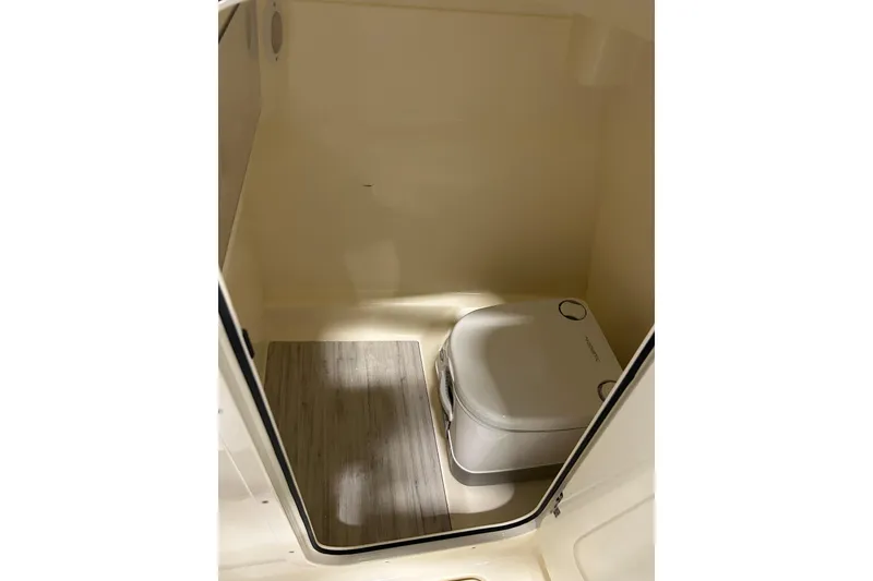 Slide: The Image of 2026 Scout 220 Dorado boat interior with portable toilet and wooden floor mat. - 8
