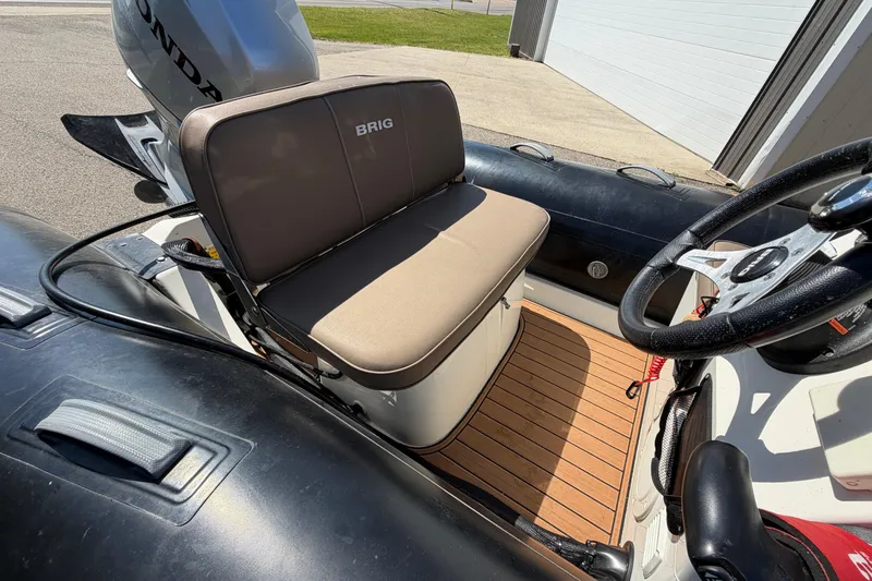 Slide: The Image of 2022 Brig Falcon 420 boat interior with Honda engine, featuring cushioned seating and steering wheel. - 17