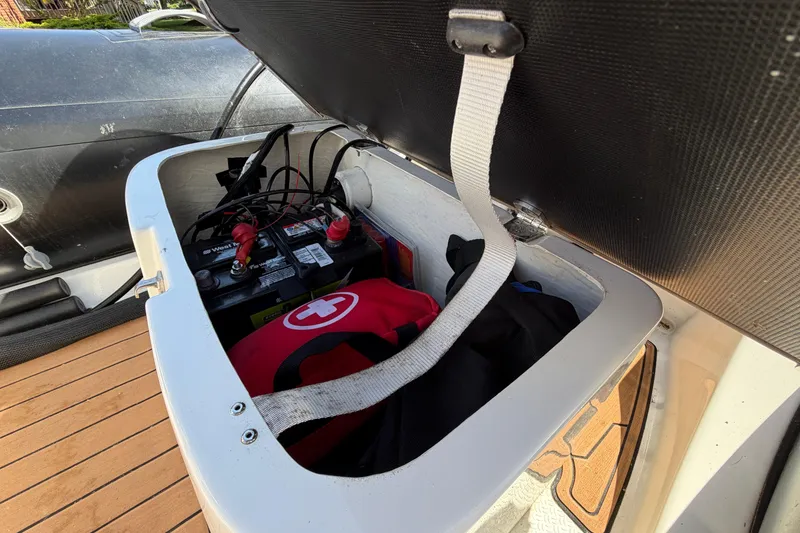 Slide: The Image of Open storage compartment in a 2022 Brig Falcon 420 boat, showing battery and first aid kit. - 20