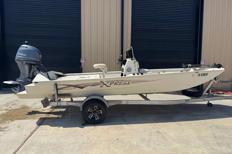 The Image of 2017 Xpress XP18CC boat with Yamaha motor on trailer, parked outside a building. - 1