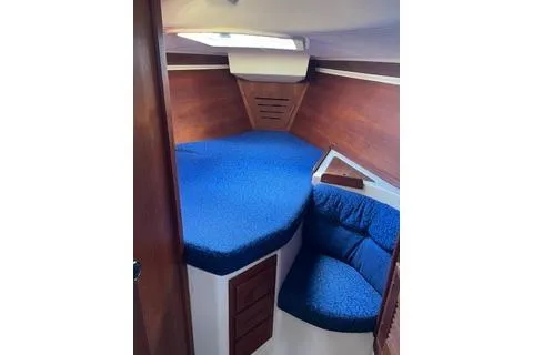 Slide: The Image of 1988 Tartan 31 sailboat interior with blue cushions and wooden accents. - 4