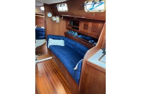 Slide: The Image of 1988 Tartan 31 yacht interior with blue seating, wooden finish, and nautical decor. - 5